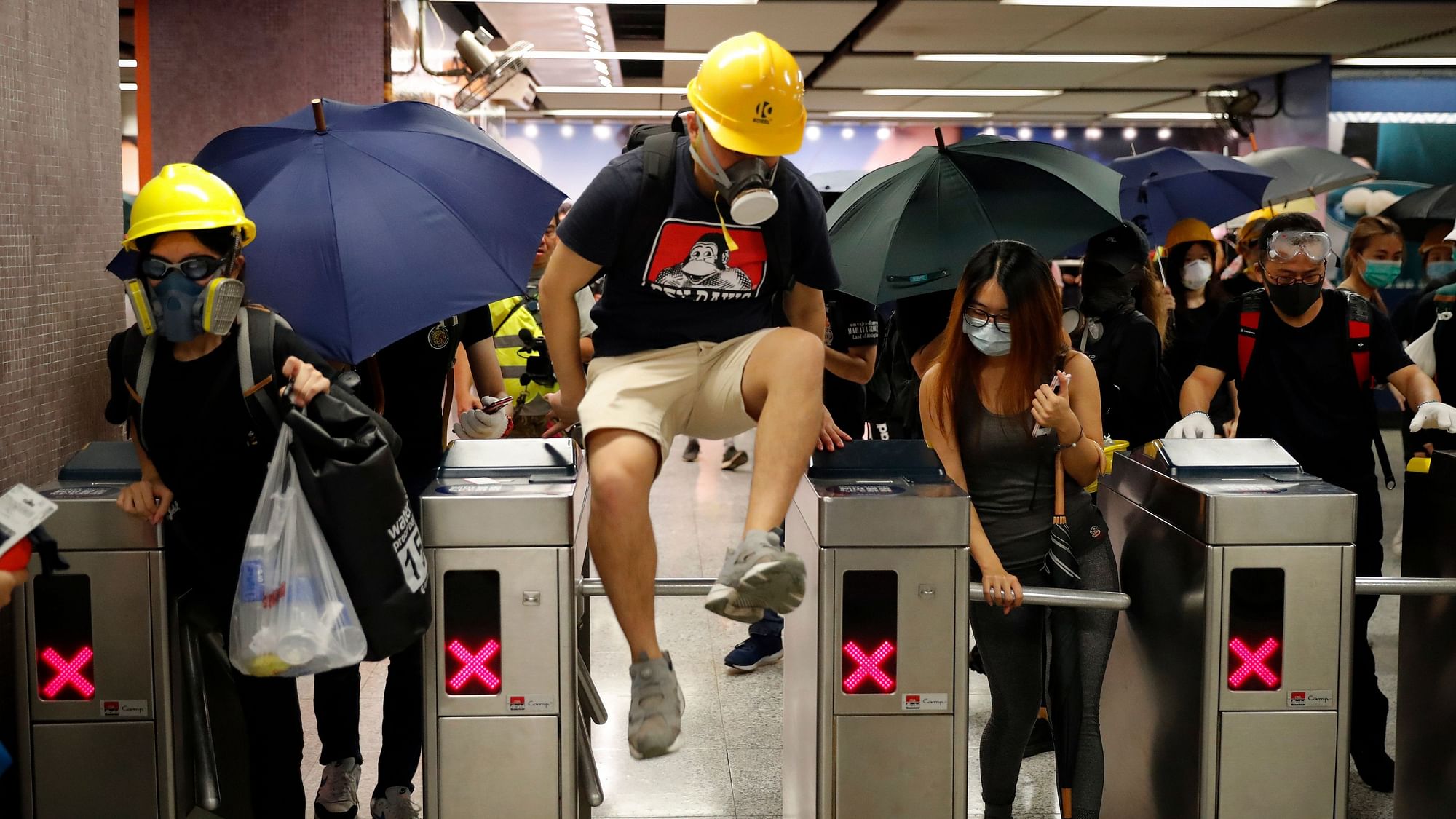 A protester jumps over the gate as protesters exit the Causeway Bay MTR station as they proceed to the anti-extradition bill protest destination, in Hong Kong on Sunday, 4 August.