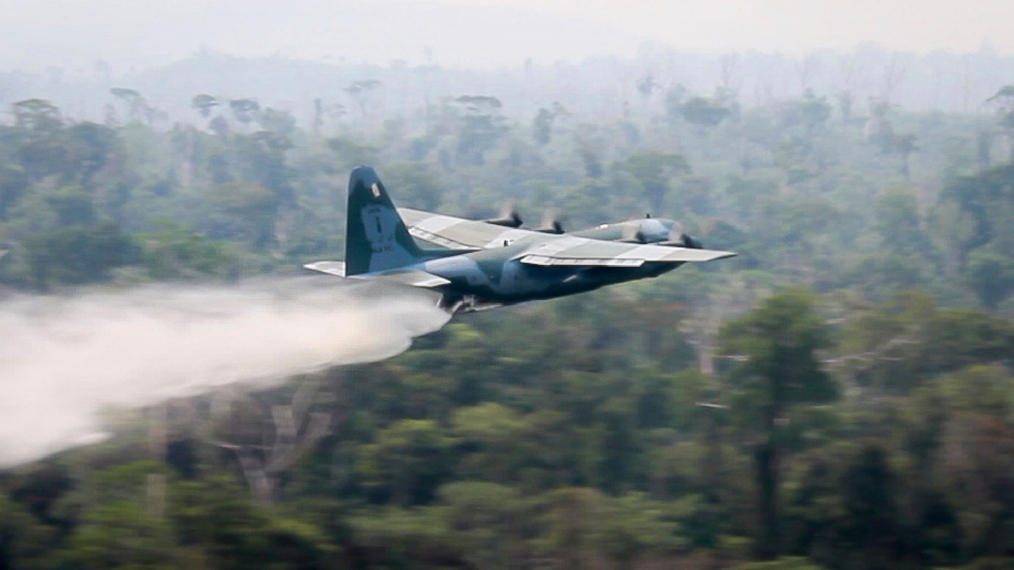 In this photo released by Brazil Ministry of Defense, a C-130 Hercules aircraft dumps water to fight fires burning in the Amazon rainforest, in Brazil.