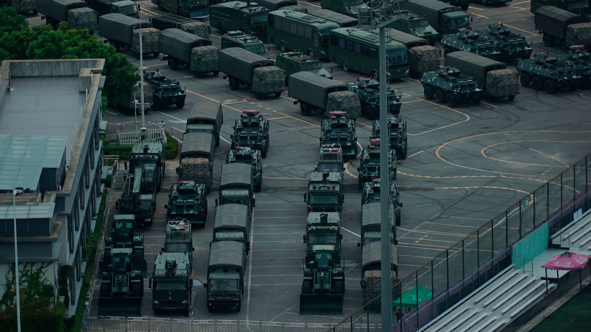 Armoured vehicles and troop trucks are parked in a lot by Shenzhen Bay Stadium in Shenzhen, China 
