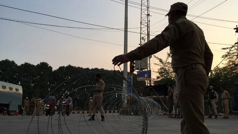 A security personnel putting up a barbwire fence to cordon off a street in Srinagar.