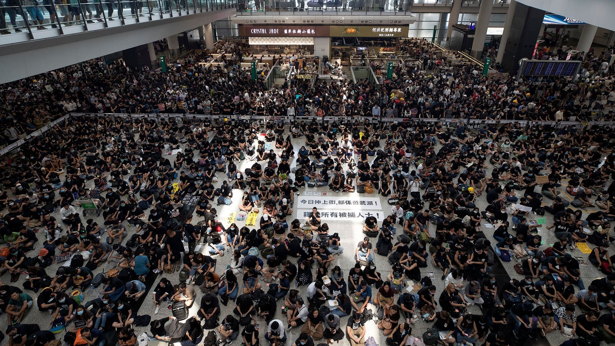 Protesters surround banners that read: “Those on the street today are all warriors!” center top, and “Release all the detainees!” during a sit-in rally at the arrival hall of the Hong Kong International airport.