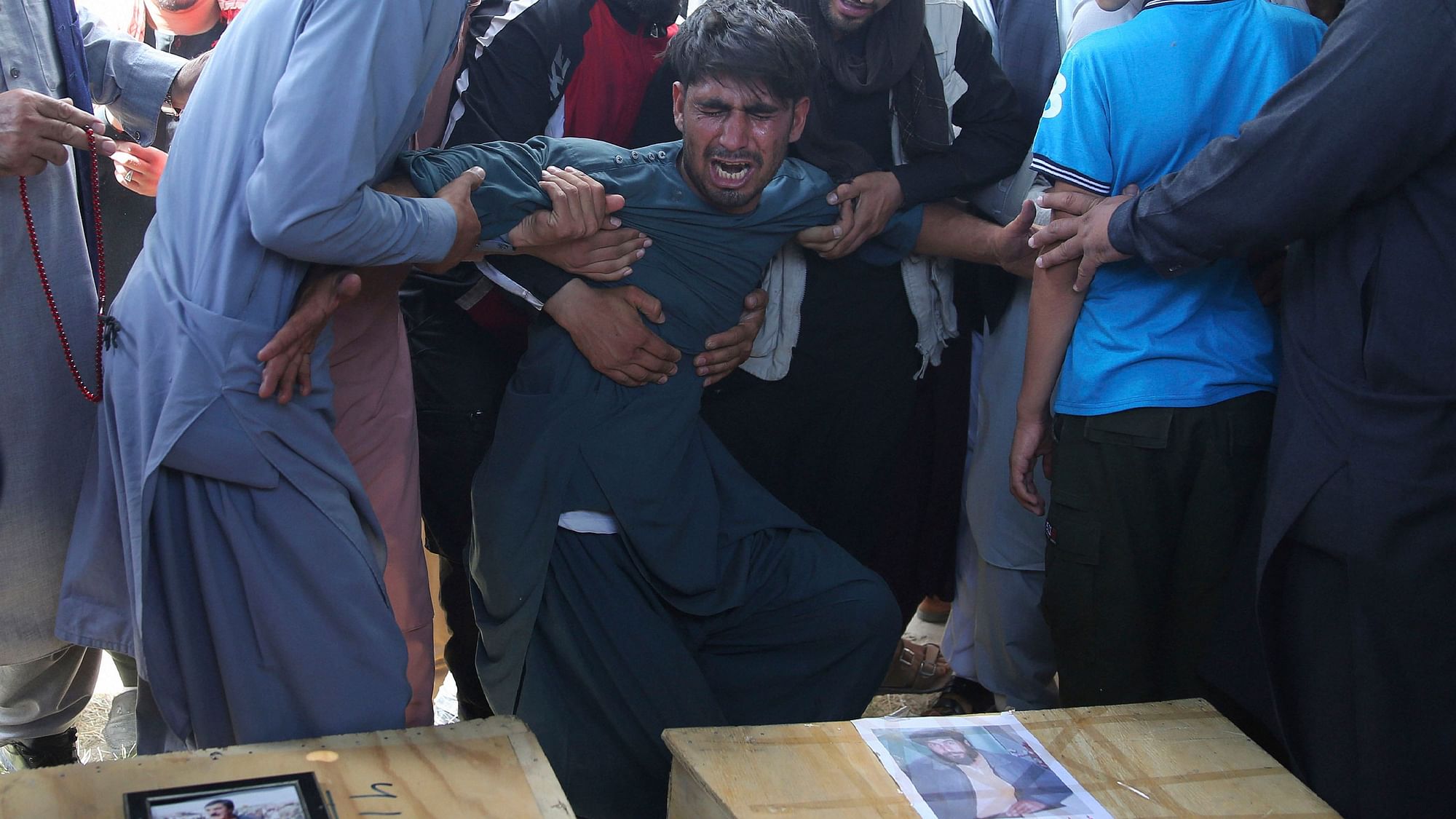 A relative wails near the coffins of victims of the Dubai City wedding hall bombing during a mass funeral in Kabul, Afghanistan, Sunday, 18 August, 2019.