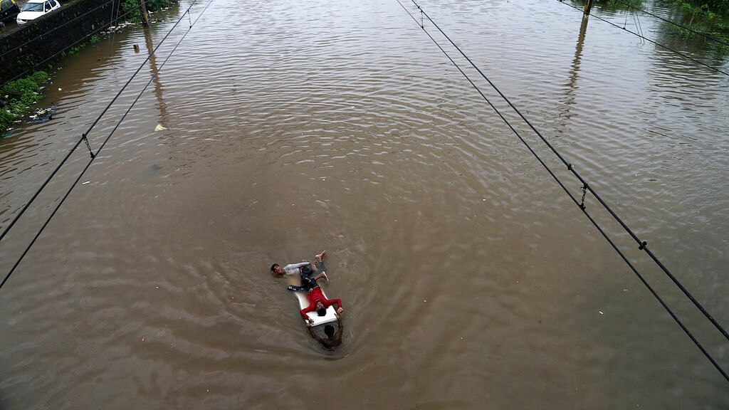 In this 4 August 2019 photo, youths play at a flooded train track following heavy monsoon rains in Mumbai.