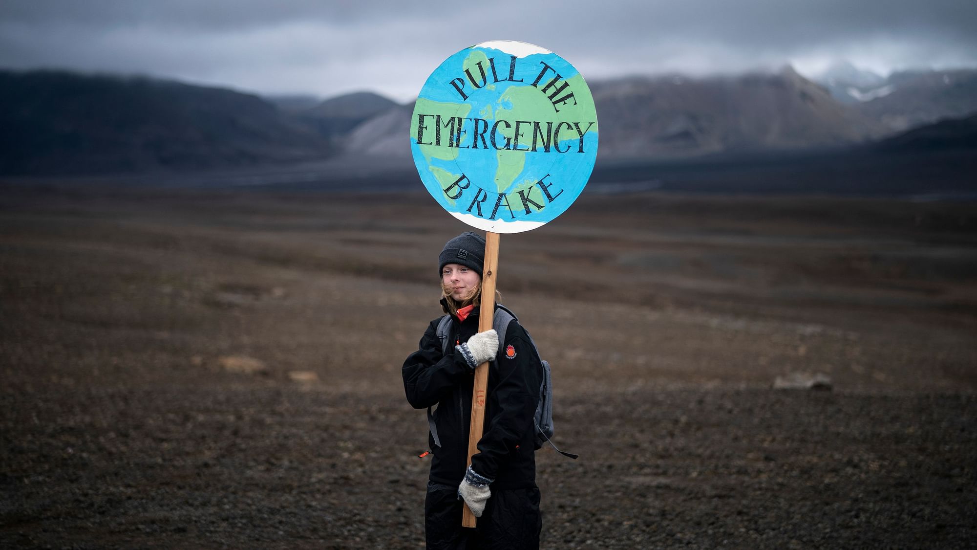 A girl holds a sign that reads ‘pull the emergency brake’ as she attends a ceremony in the area which once was the Okjokull glacier, in Iceland, 18 August 2019.