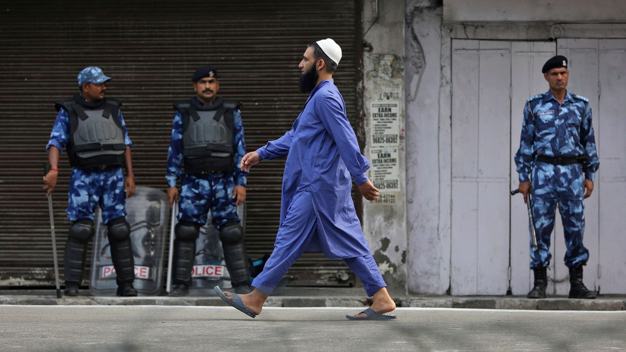 An Indian Muslim man walks past Indian paramilitary soldiers after offering prayer during Eid al-Adha in Jammu.
