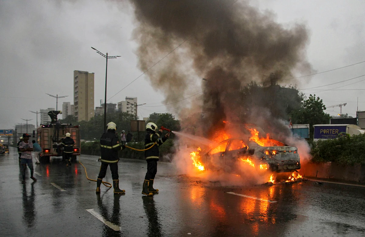 Fire personnel douse the flames on a car that caught fire on Chembur Road in Mumbai, Thursday, 26 September.