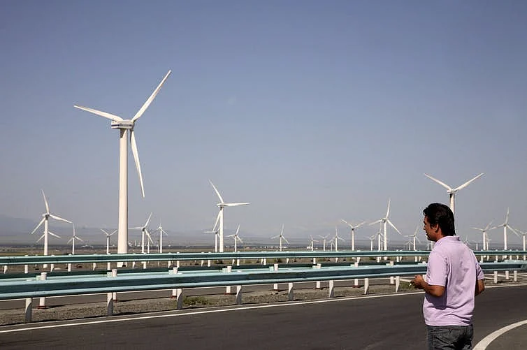 A man standing near a wind farm near Urumuqi, China.