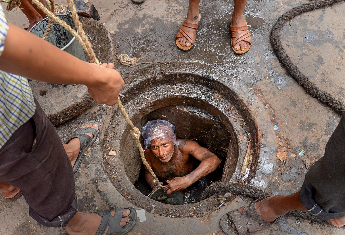 A Municipal Corporation worker enters a manhole for sewage cleaning at Mahatma Gandhi Road, in Kolkata. 