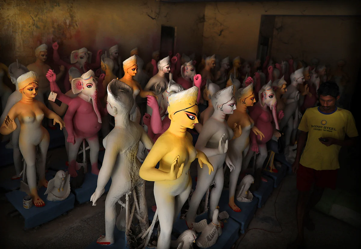 An artist walks past unfinished clay idols of Hindu goddess Durga at a makeshift studio in New Delhi, India, Wednesday, 25 September. 
