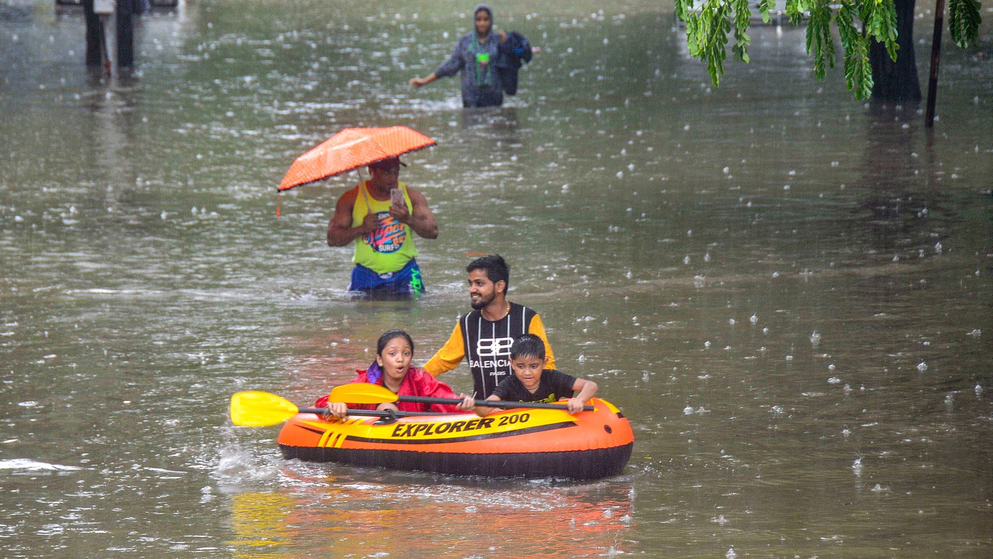 People commute through a waterlogged street on foot and via inflatable boat, following heavy monsoon rain in Mumbai on Wednesday.