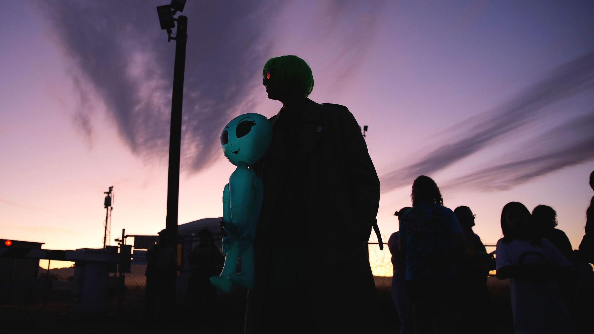 Chase Hansen holds an inflatable alien near an entrance to the Nevada Test and Training Range near Area 51, Friday