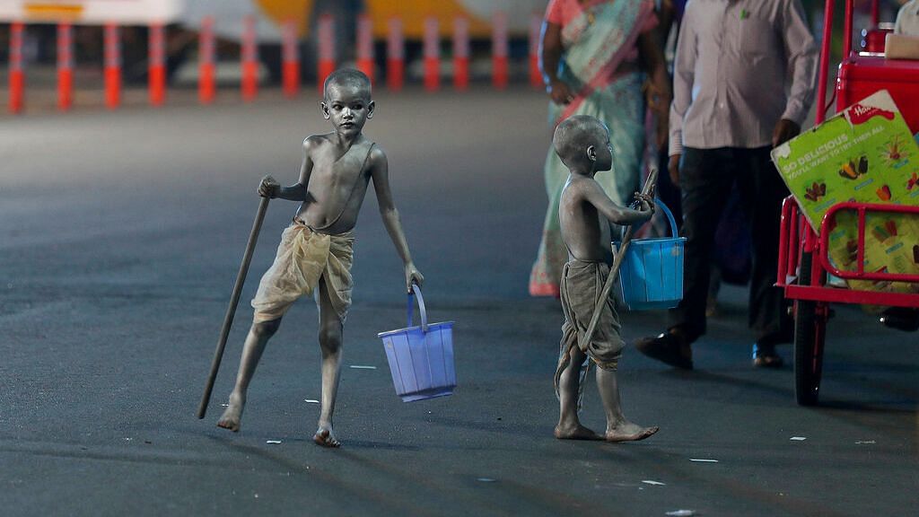 Young boys with their bodies painted and dressed as Mahatma Gandhi seek alms at a traffic intersection in Hyderabad.