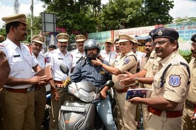 Hyderabad: Policemen give a helmet to a motorcyclist instead of challans in Hyderabad. (Photo: IANS)