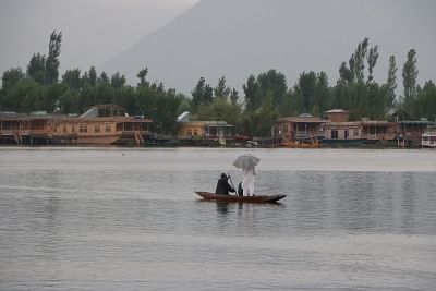 Srinagar: A man enjoys boat ride in the Dal Lake amidst rains in Srinagar on July 18, 2019. (Photo: IANS)