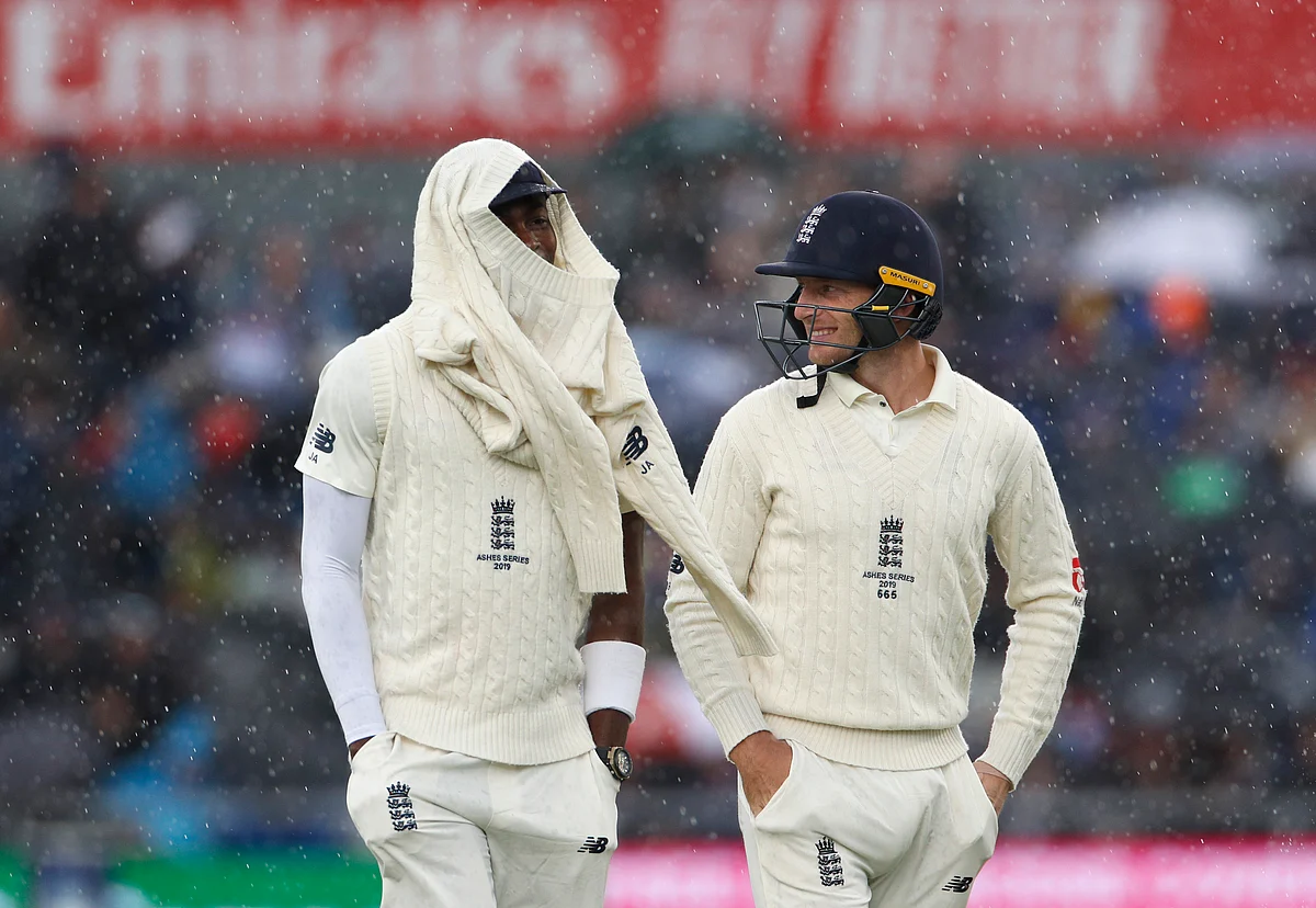 England’s Jofra Archer, left, and Jos Buttler leave the field as it rains during day one of the fourth Ashes Test cricket match.