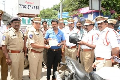 Hyderabad: Policemen give a helmet to a motorcyclist instead of challans in Hyderabad. (Photo: IANS)