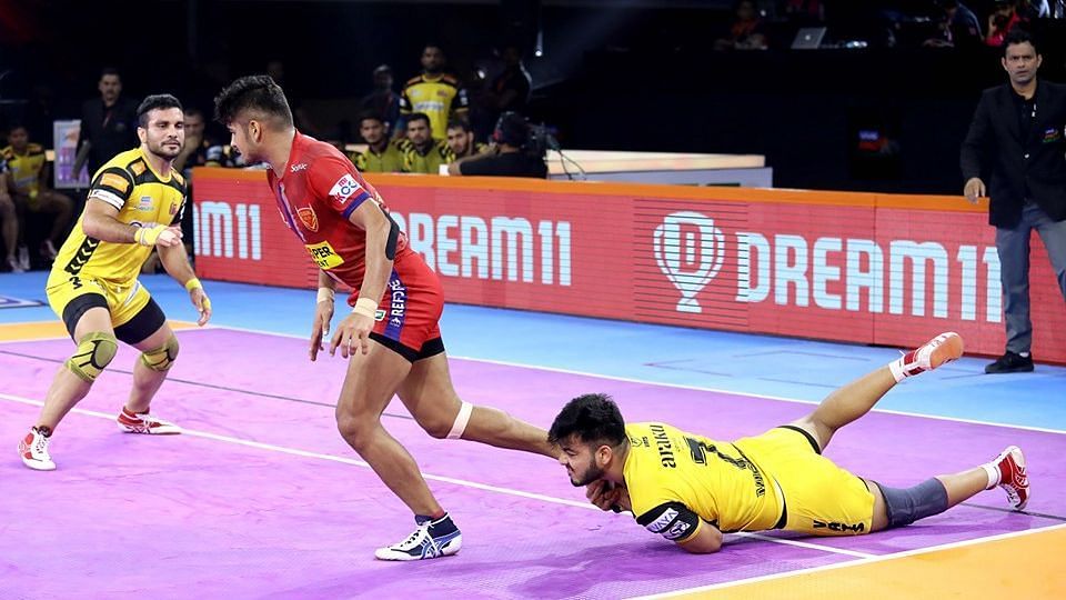 Defender trying to hold on to Naveen Kumar during a game.