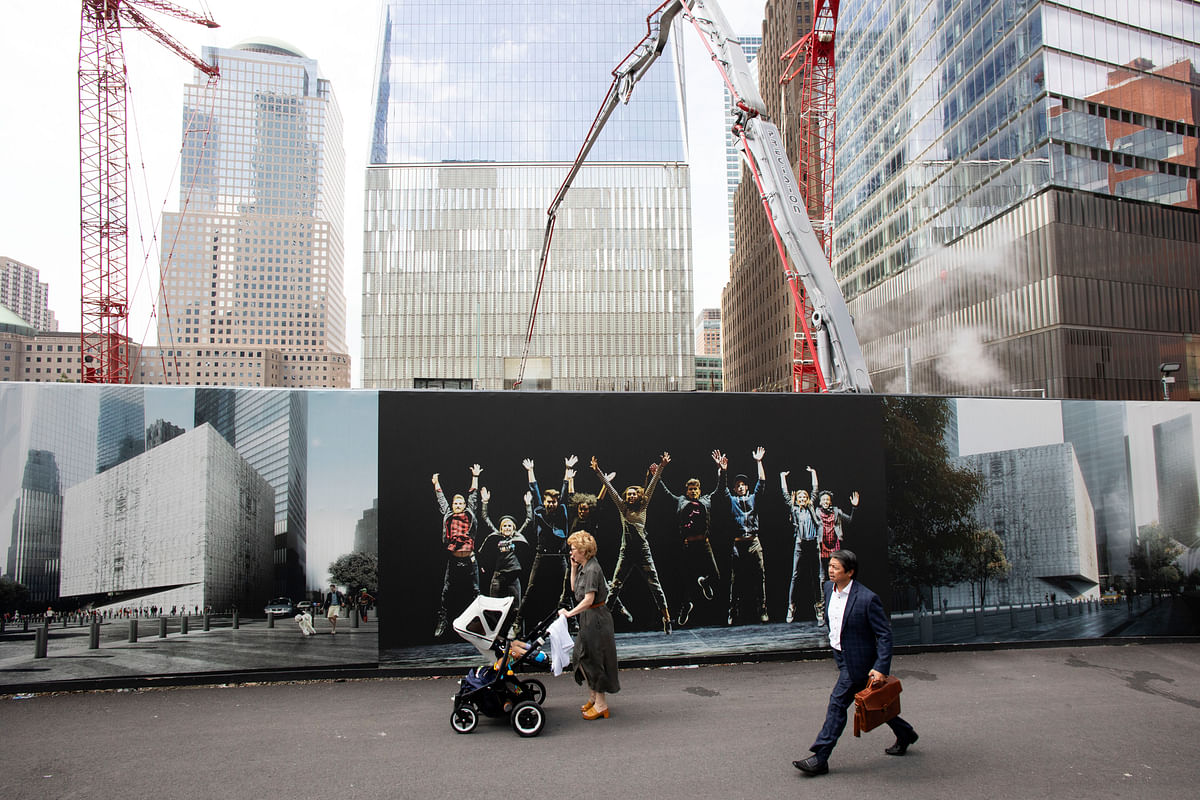 People walk by murals promoting the future site of the Ronald O. Perelman Performing Arts Center as cranes work over the site at the World Trade Center, Monday, on 9 September.