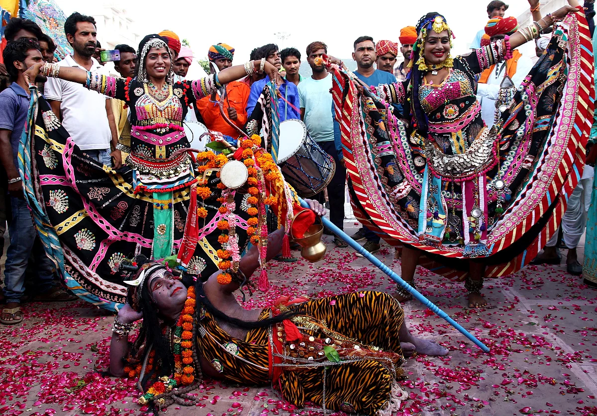 A man dressed as Lord Shiva poses as Rajasthani folk artists dance on the eve of World Tourism Day in Pushkar, Rajasthan, Thursday, 26 September.