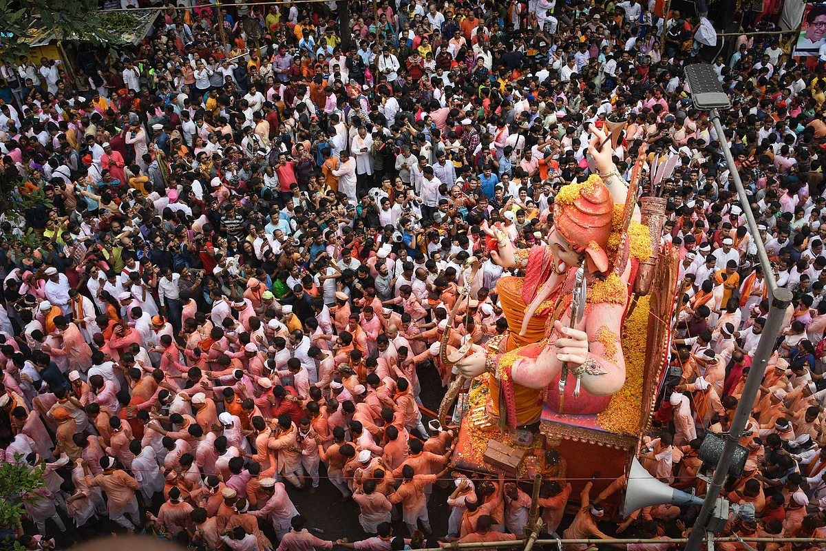 People watch as devotees carry an idol of Lord Ganesha for immersion, which marks the end of Ganesh Utsav celebrations, in Mumbai, on Thursday, 12 September 2019. 