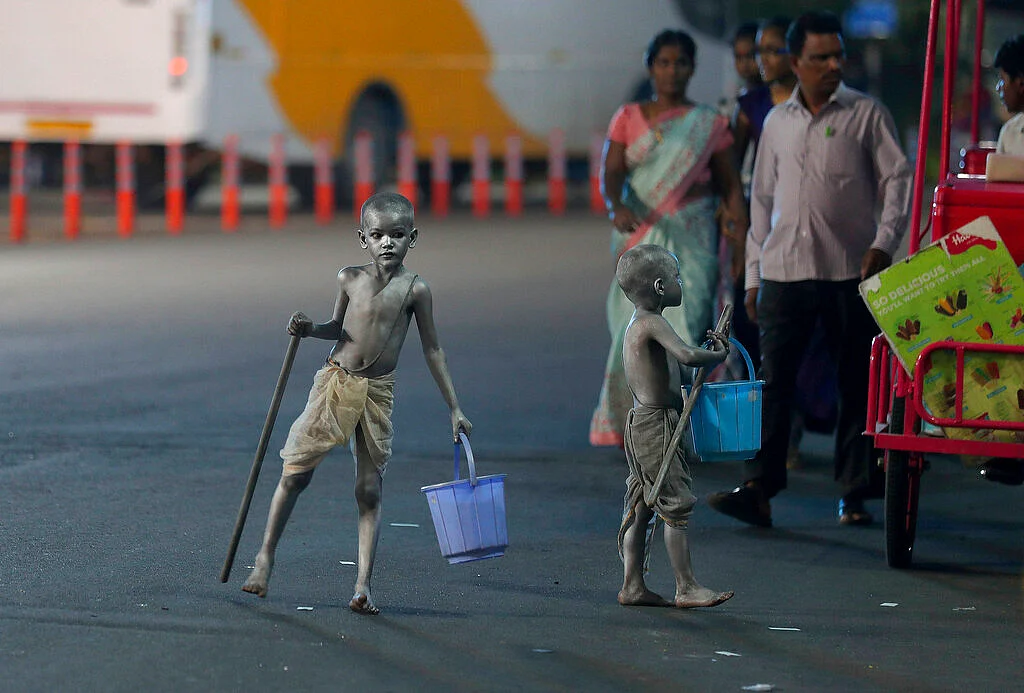 Young boys with their bodies painted and dressed as Mahatma Gandhi seek alms at a traffic intersection in Hyderabad.