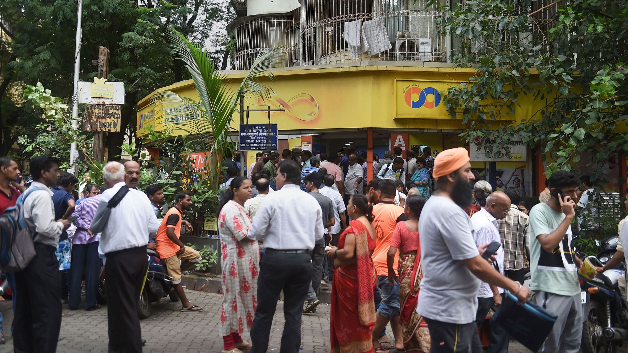 Customers stand outside the Punjab and Maharashtra Cooperative Bank at GTB Nagar in Mumbai on Tuesday.