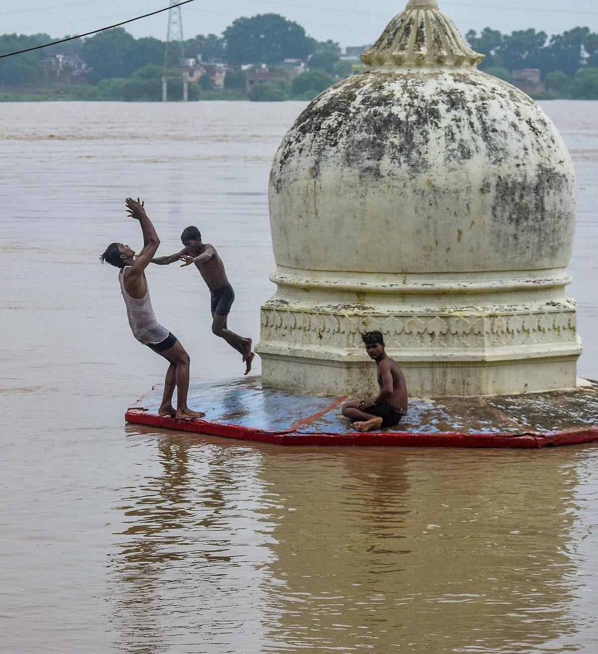 Youths jump into the floodwater at a flood-hit area following the rise in Ganga River due to monsoon rainfall, in Prayagraj.