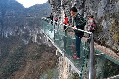 TONGREN, Feb. 24, 2016 (Xinhua) -- Tourists walk on a glass skywalk in the National Mine Park of Tongren City, southwest China
