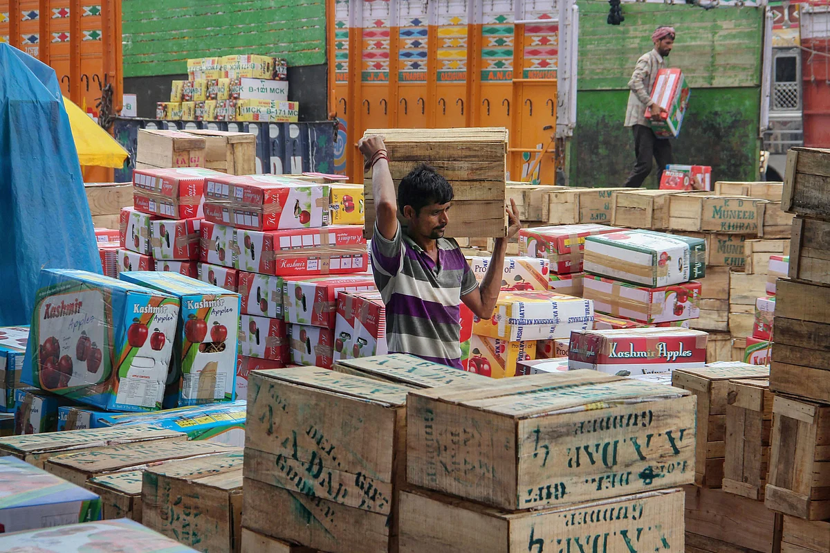 A worker carries a box of Kashmiri apples for sale at Narwal fruit market, on the outskirts of Jammu, Wednesday, 25 September.