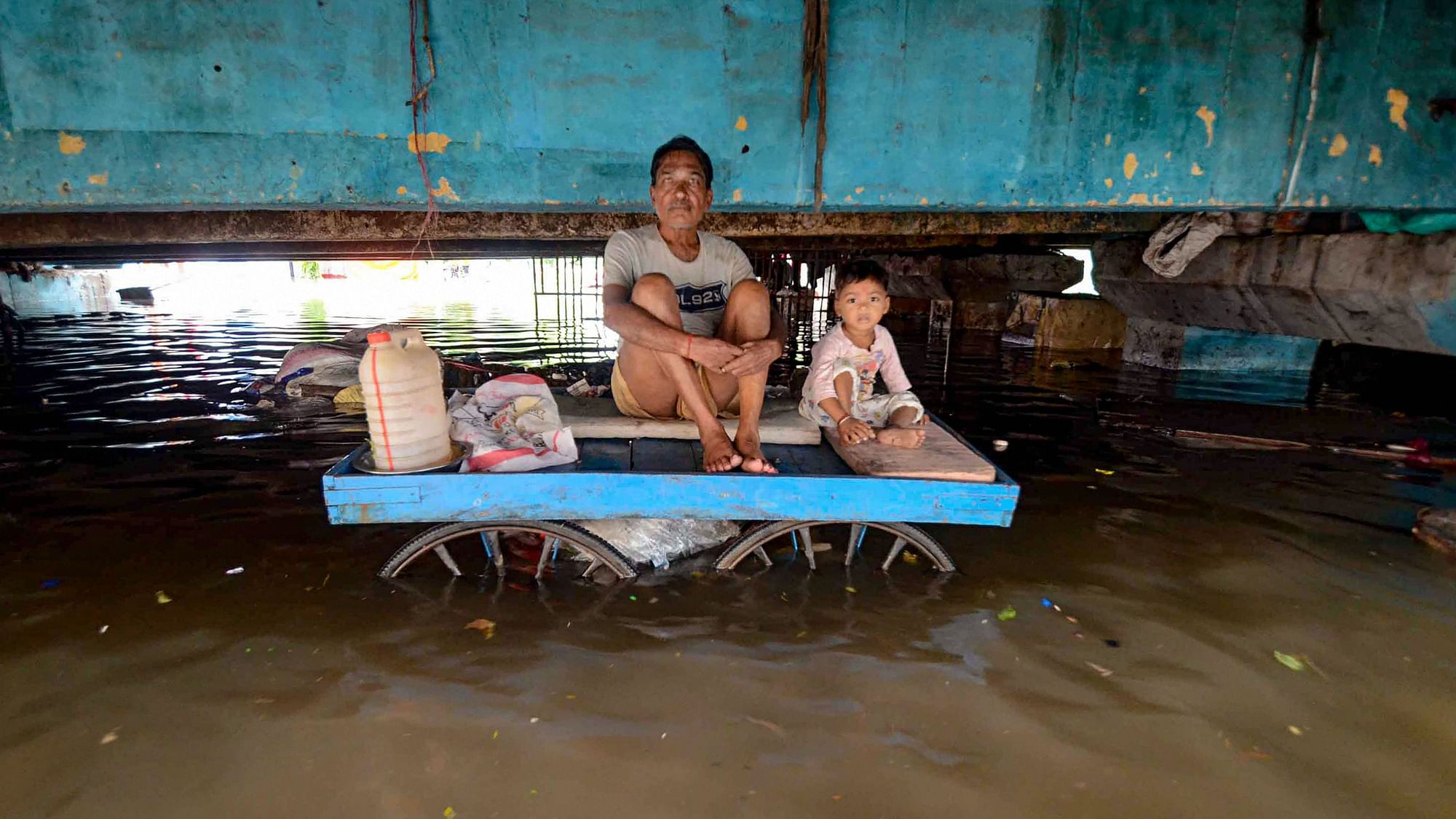 A person sits with a child on a cart in an area affected by waterlogging following heavy monsoon rainfall in Patna on Monday, 30 September.