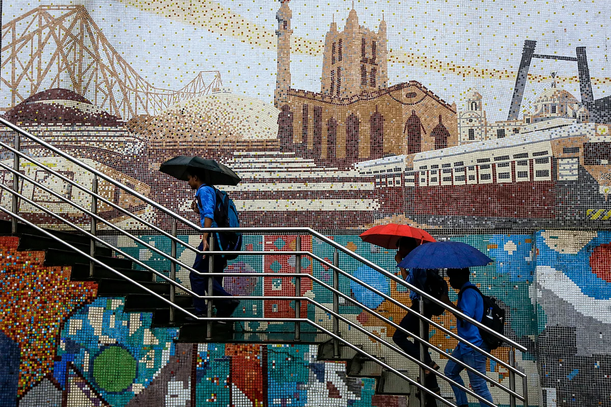 Commuters climb a staircase in the backdrop of murals of city heritage sites during monsoon rains in Kolkata, India, Tuesday, 24 September.