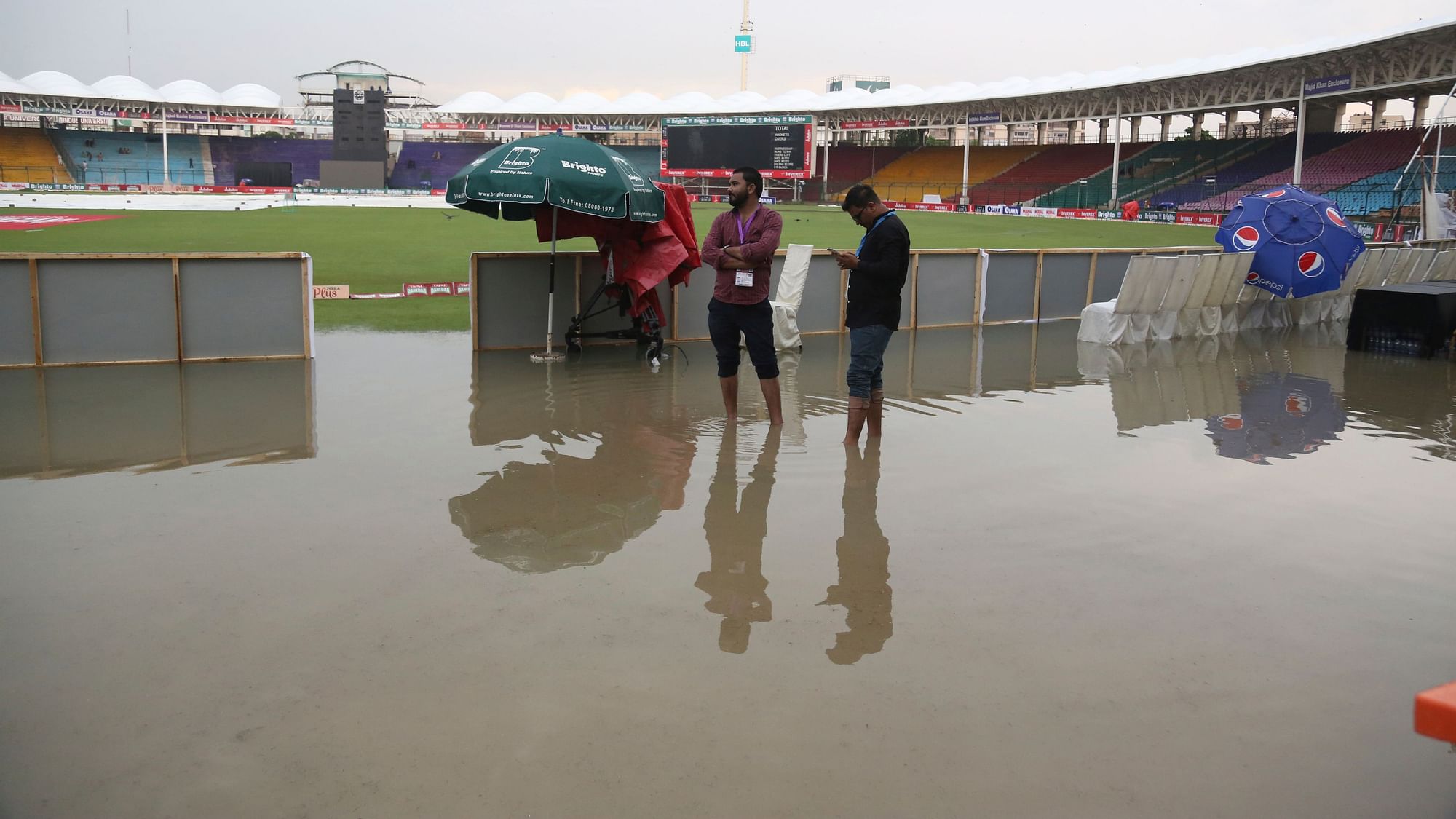Ground officials stand at the National Stadium after rain in Karachi in Pakistan on Friday.