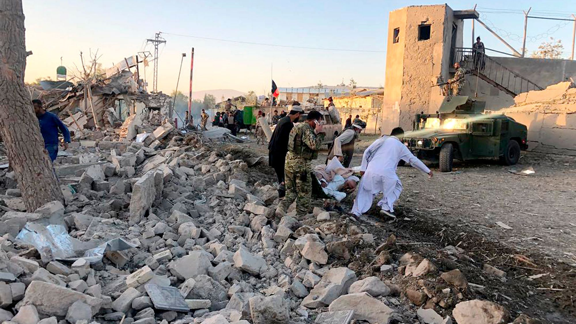Afghan security members and people work at the site of a suicide attack in Zabul, Afghanistan.