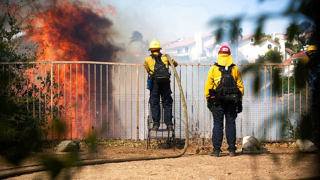 Orange County firefighters work hot spots at Porter Ranch Estates after the Saddleridge Fire burned through during Santa Ana wind conditions.