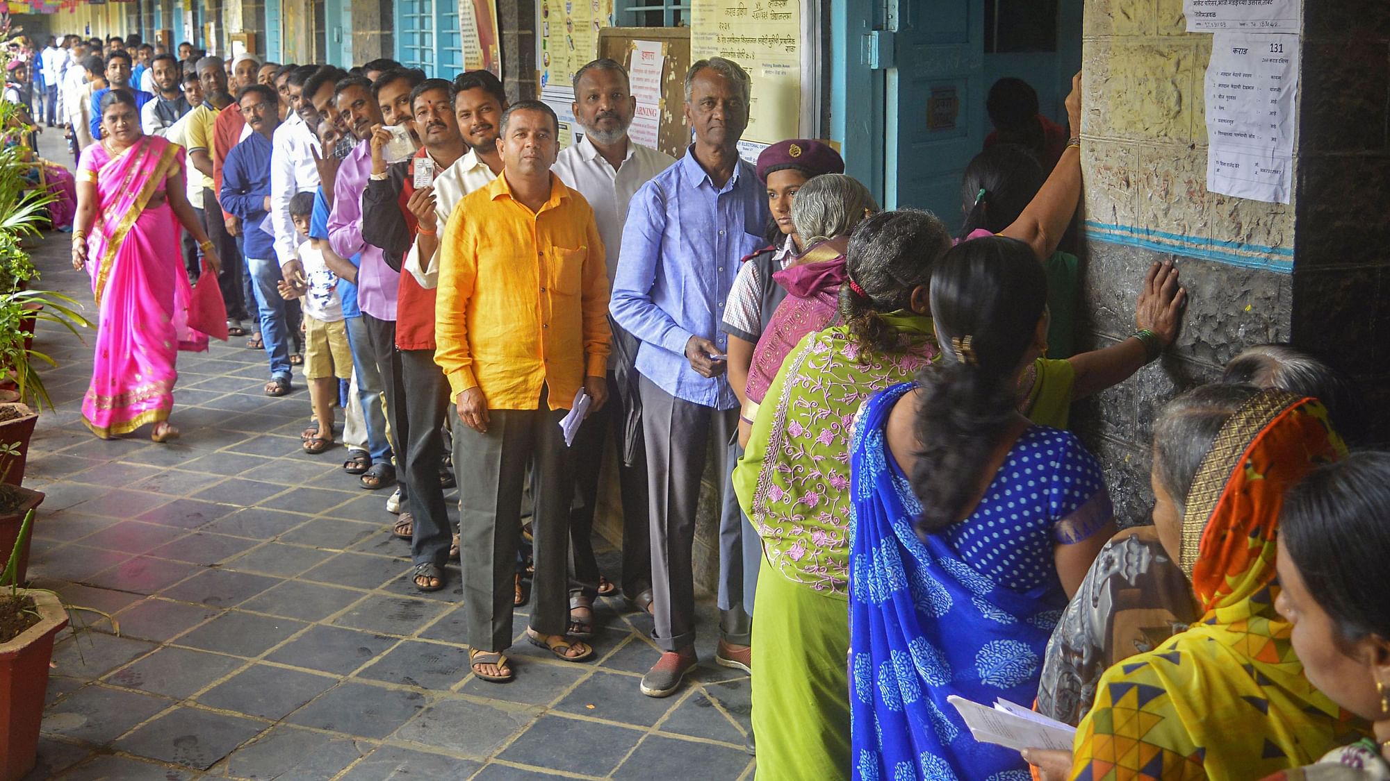  Voters stand in a queue as they wait to cast their votes at a polling station for the Maharashtra Assembly elections, in Karad.