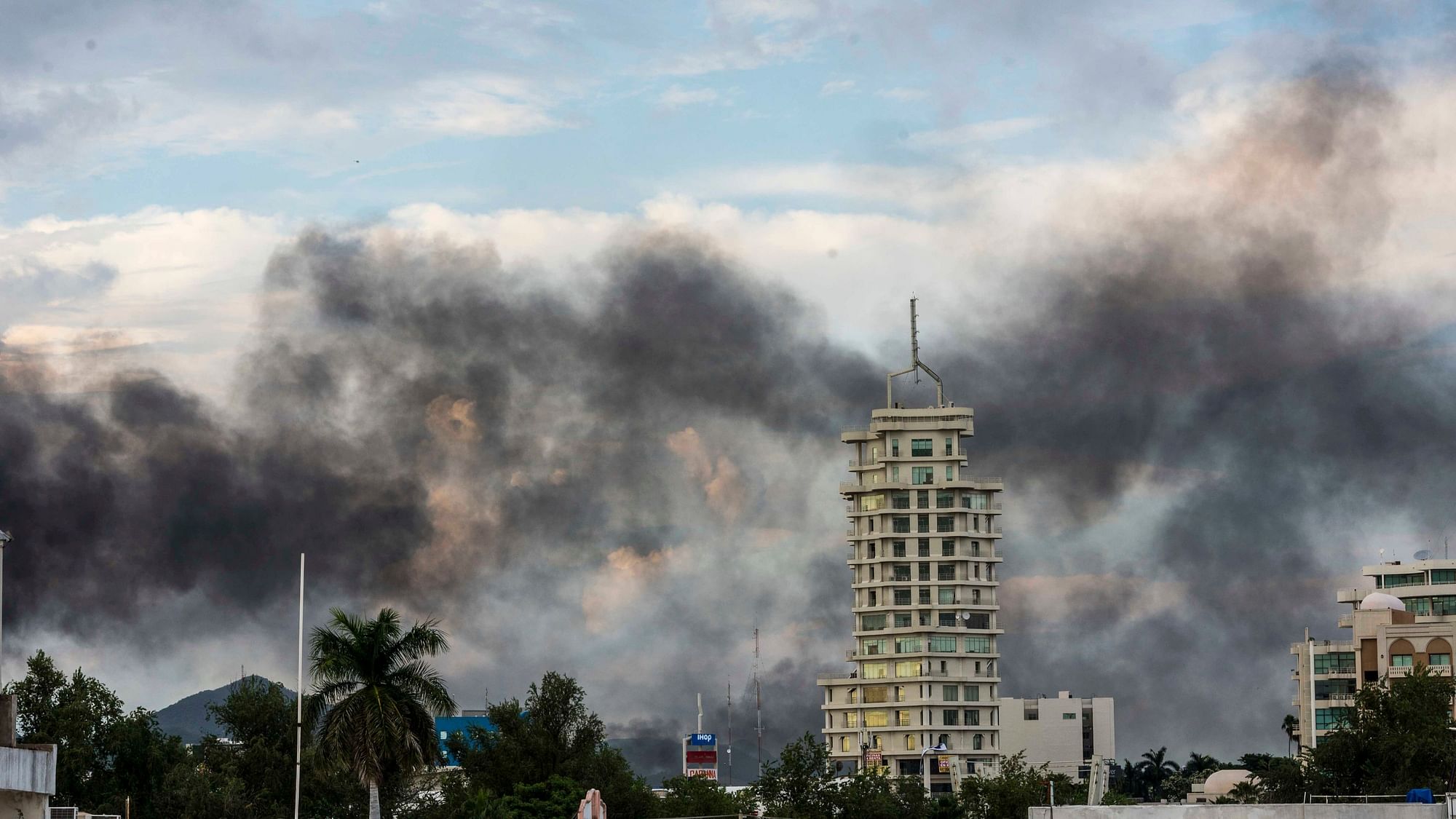 Smoke from burning cars rises after an intense gunfight broke out, burning vehicles and blocking roads in the capital of Mexico’s Sinaloa state.