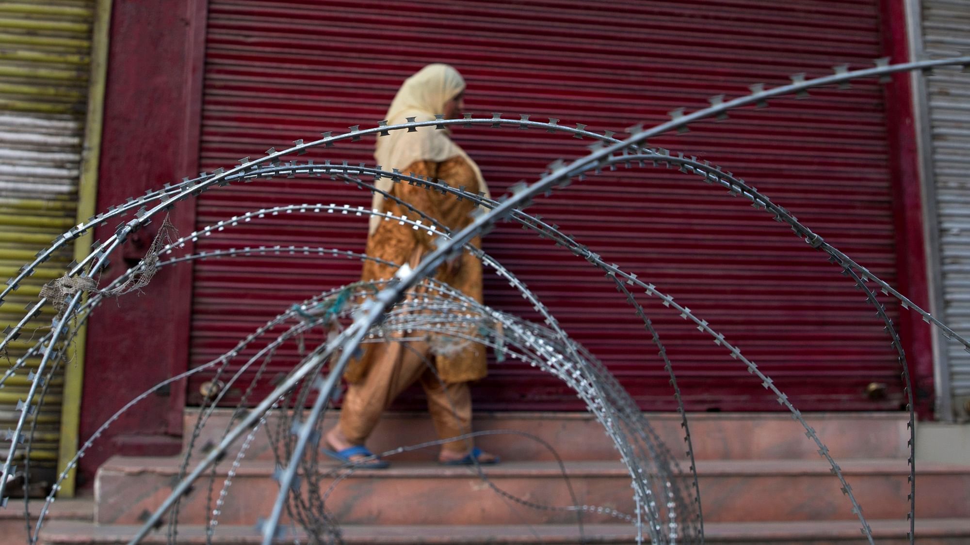 A Kashmiri woman walks past a barbed wire barricade set up by paramilitary soldiers during restrictions in Srinagar.