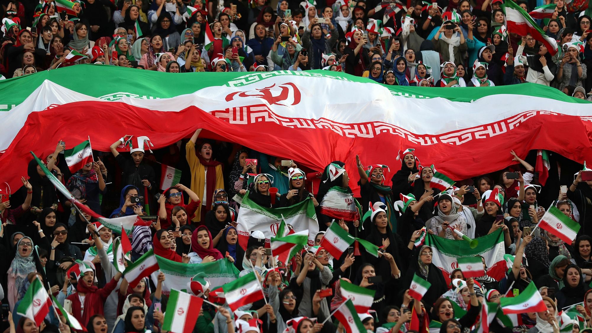 Iranian women cheer as they hold a huge Iranian flag during a soccer match between their national team and Cambodia in the 2022 World Cup qualifier at the Azadi (Freedom) Stadium in Tehran, Iran, Thursday, Oct. 10, 2019.&nbsp;
