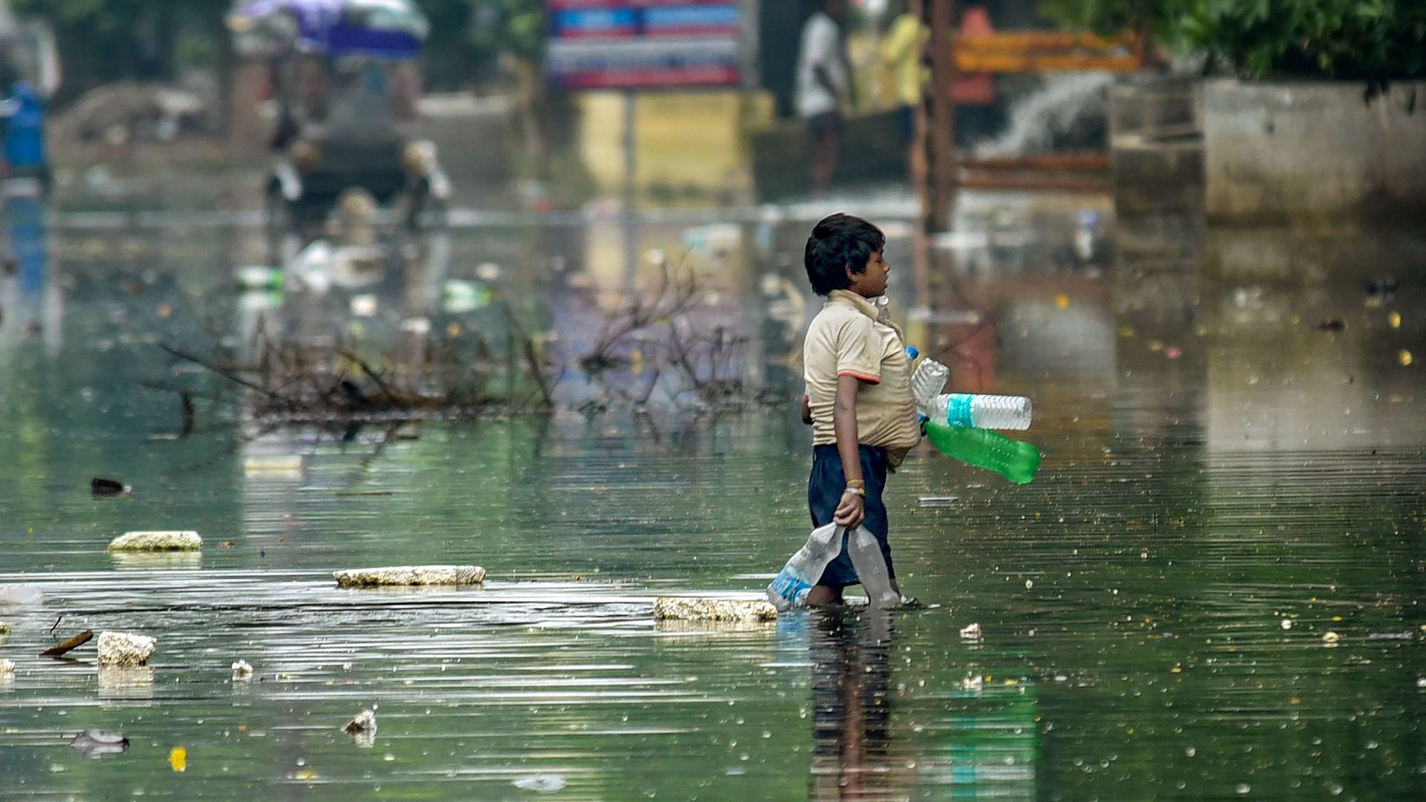 A rag-picker collects plastic drinking bottles floating on floodwaters after water levels receded at Rajendra Nagar in Patna on Sunday, 6 October.&nbsp;