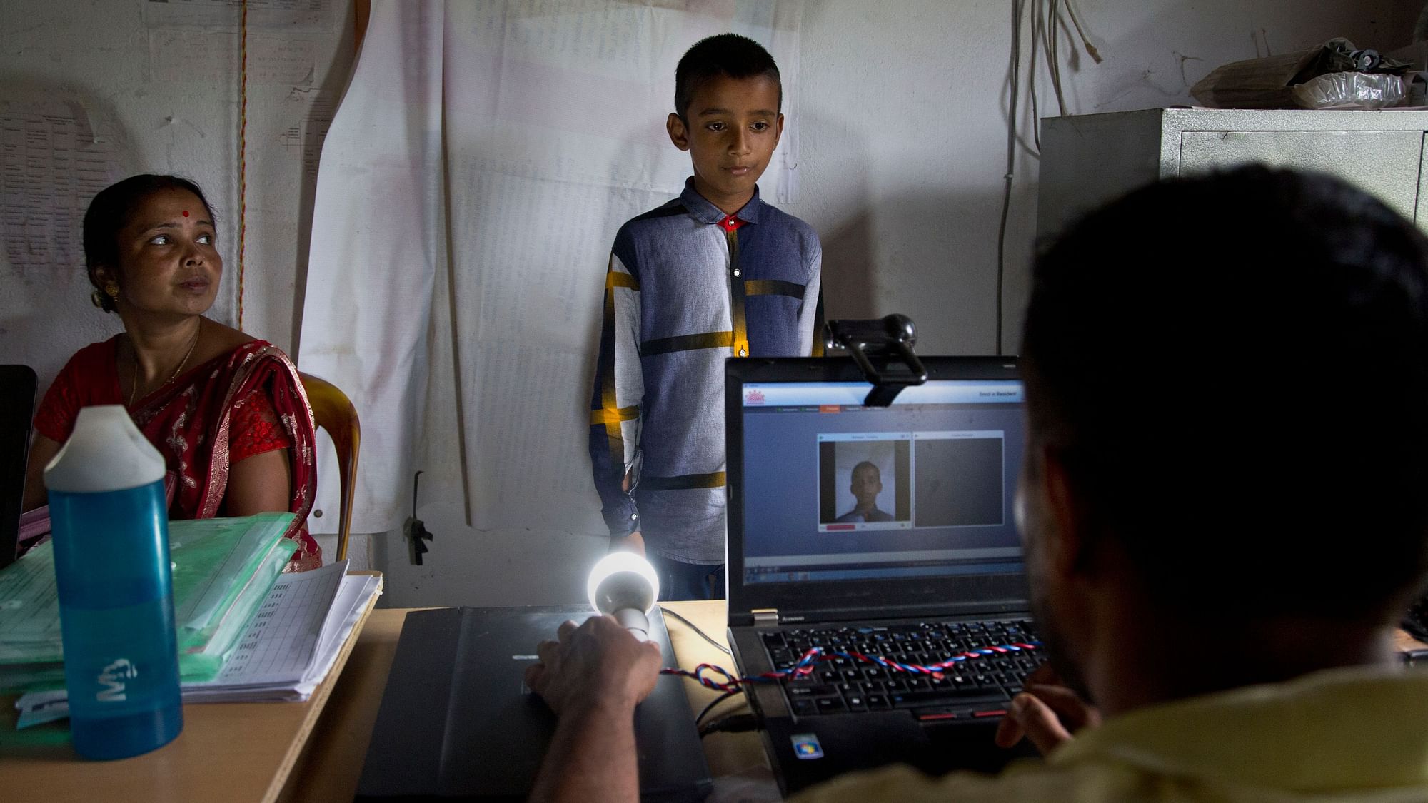 A National Register of Citizens (NRC) officer takes a photograph of a boy at an NRC centre.