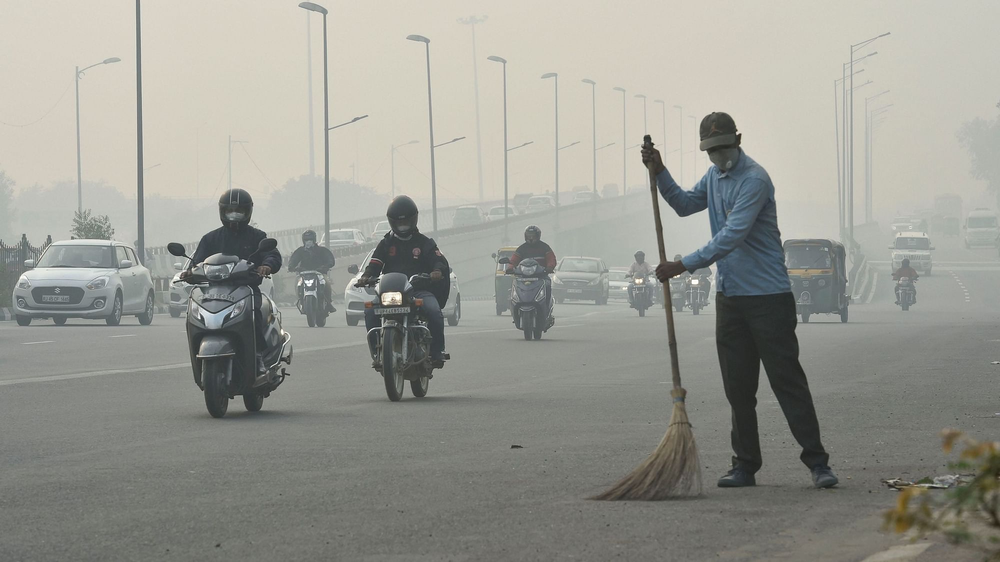  A civic worker, wearing an anti-pollution mask, sweeps the road amid heavy smog, in New Delhi.