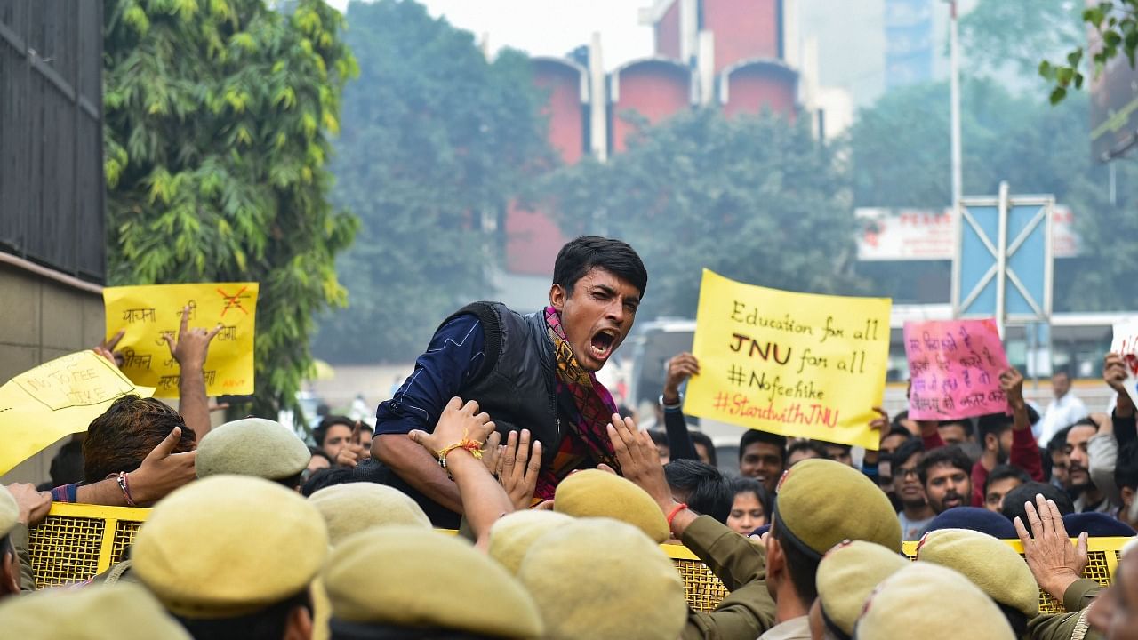 A student protesting in Jawaharlal Nehru University against the fee hike trying to resist the police personnel deployed.