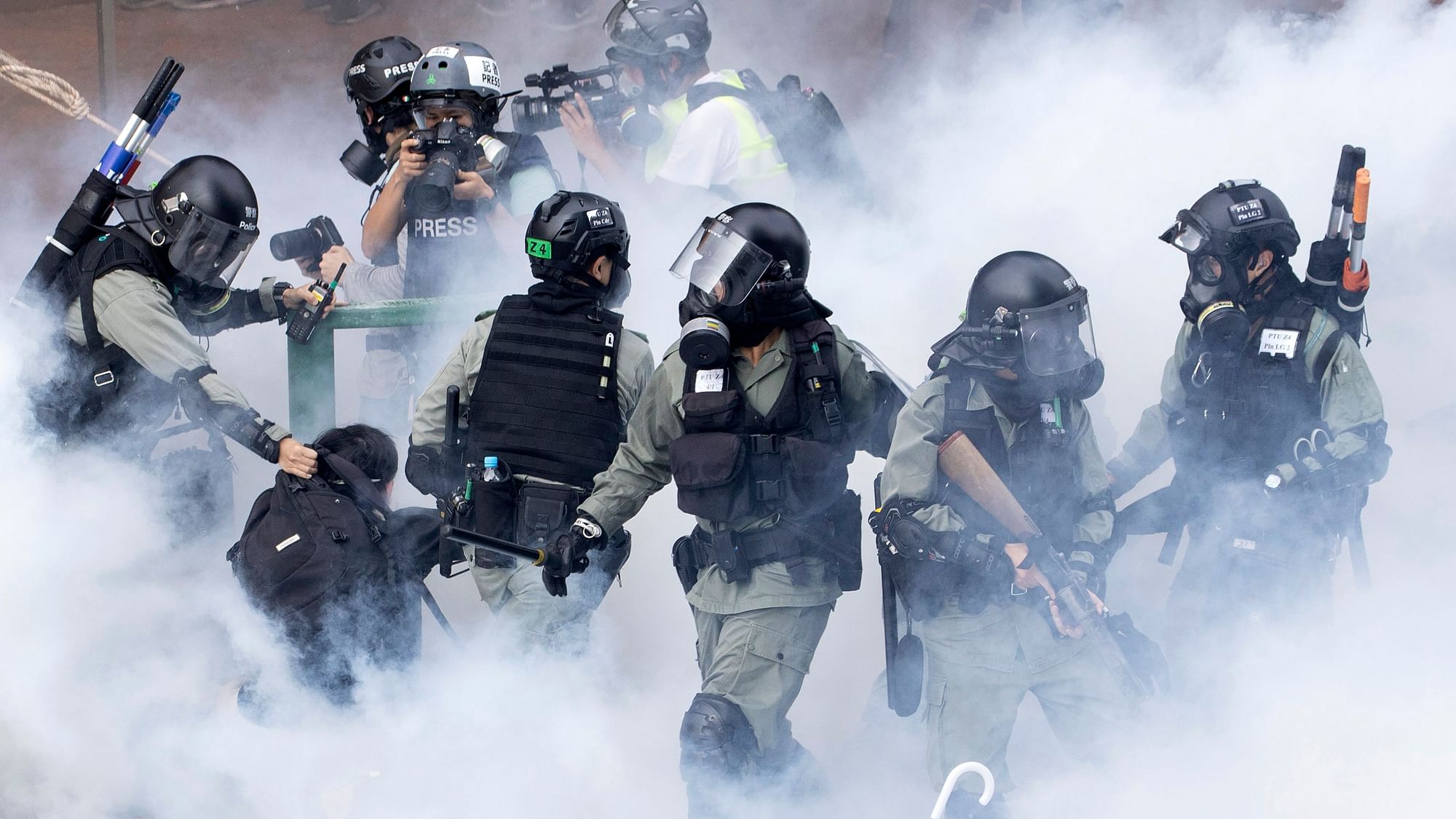 Police in riot gear move through a cloud of smoke as they detain a protester at the Hong Kong Polytechnic University in Hong Kong on Monday, 18 November 2019.