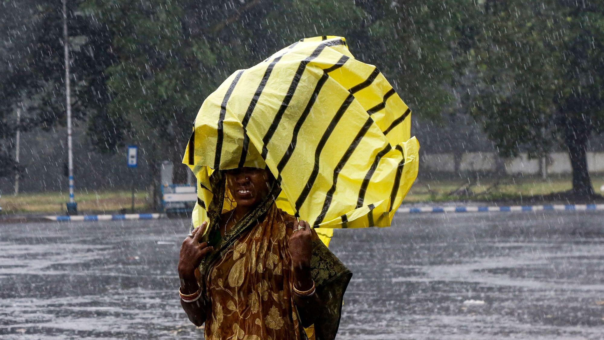 A woman covers her head with a plastic sheet as it rained in Kolkata.&nbsp;