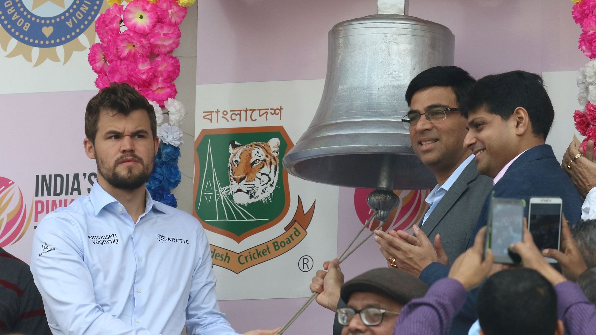 Magnus Carlsen and Viswanathan Anand ring the bell at the start of Day 2 of the India vs Bangladesh Test held at the Eden Gardens Stadium.