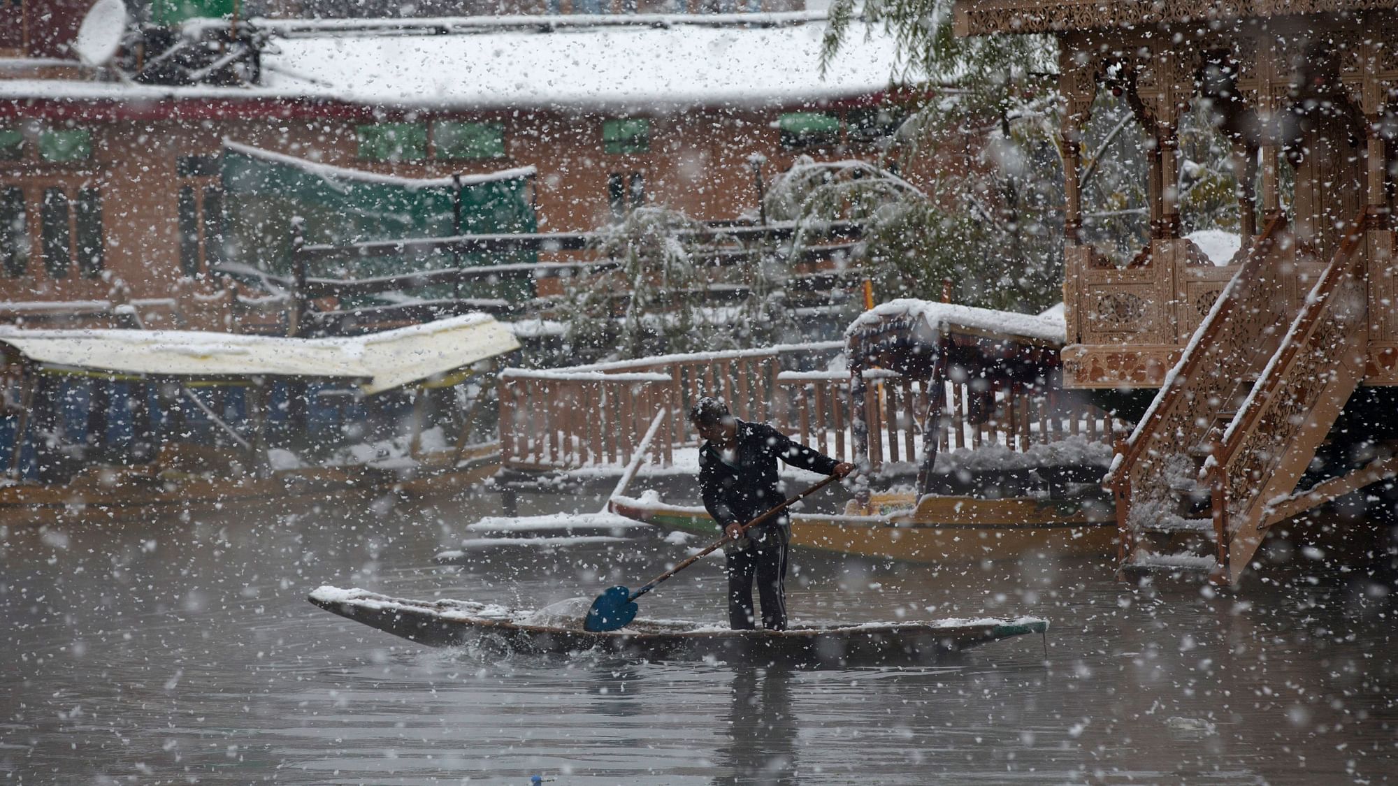 A man rows his boat as it snows in Srinagar on Thursday.&nbsp;