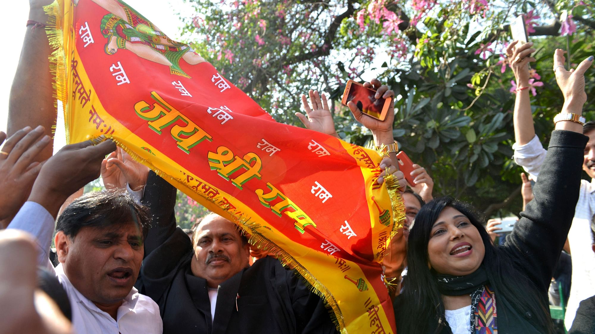 People wave a flag that reads ‘Glory to lord Rama’ as they celebrate the verdict outside the Supreme Court in New Delhi, on Saturday, 9 November.