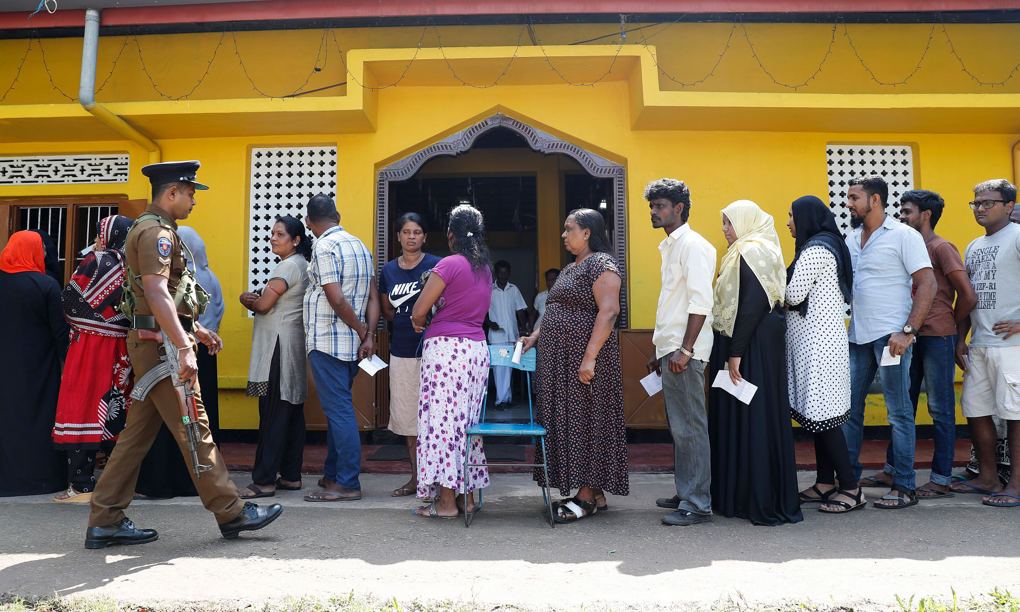 Sri Lankans queue to cast their votes as a police officer stands guard at a polling station during the presidential election in Colombo, Sri Lanka, Saturday, 16 November 2019. Polls opened in Sri Lanka’s presidential election Saturday after weeks of campaigning that largely focused on national security and religious extremism in the backdrop of the deadly Islamic State-inspired suicide bomb attacks on Easter Sunday. 