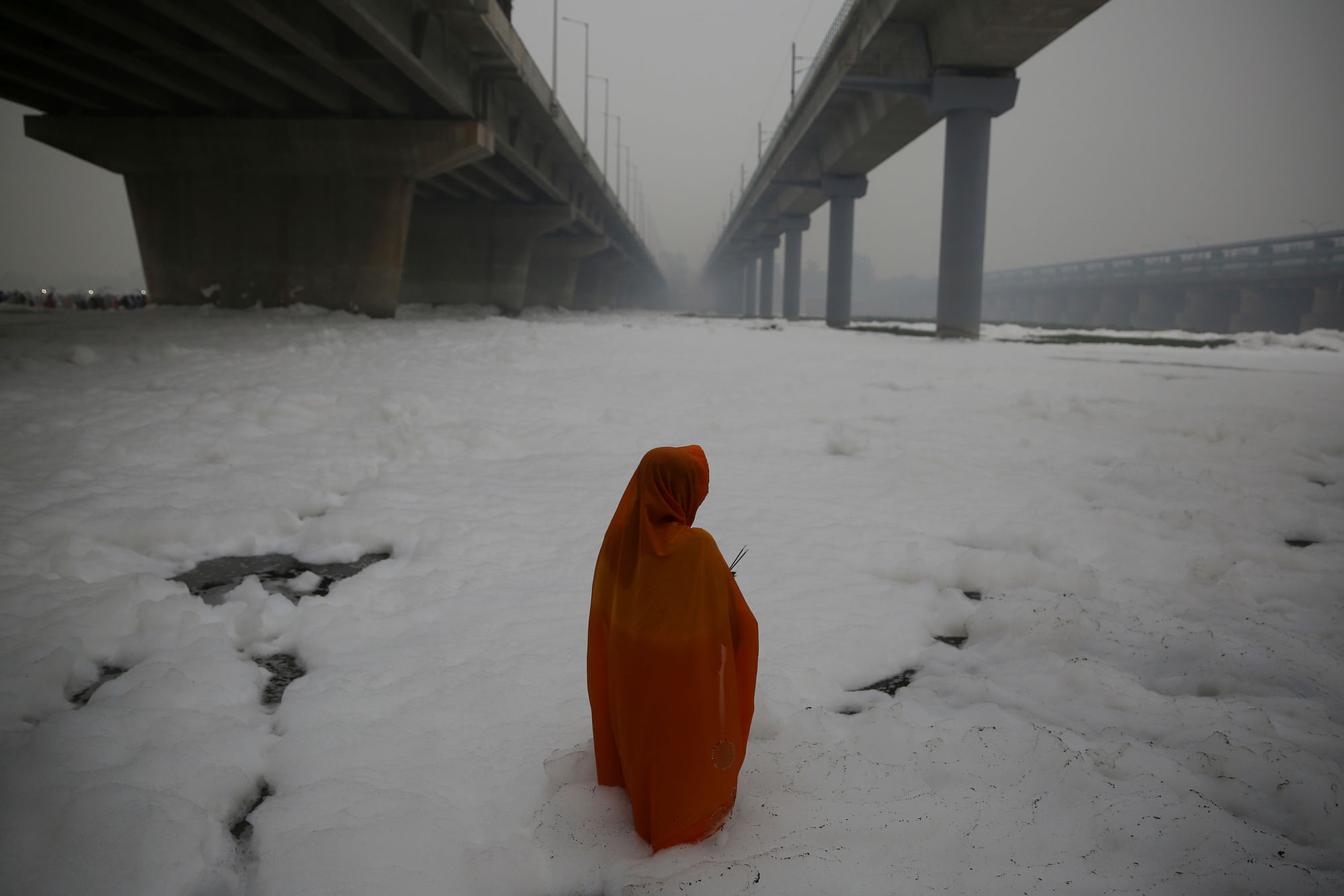 An Indian Hindu devotee performs rituals in Yamuna river, covered by chemical foam caused due to industrial and domestic pollution during Chhath Puja festival in New Delhi.
