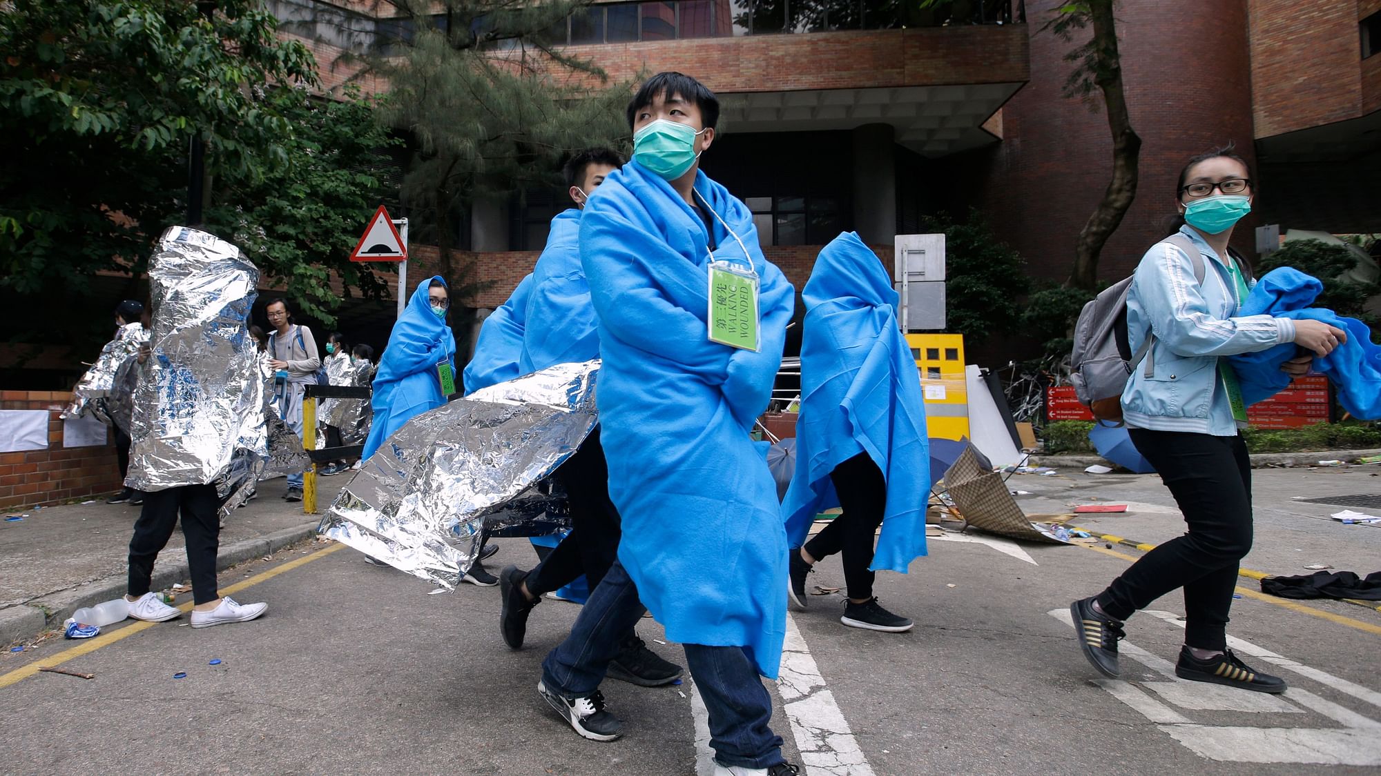 Injured protesters wrapped in blankets, walk through the campus of the Hong Kong Polytechnic University in Hong Kong, Tuesday, Nov. 19, 2019. About 100 anti-government protesters remained holed up at the Hong Kong university Tuesday as a police siege of the campus entered its third day.